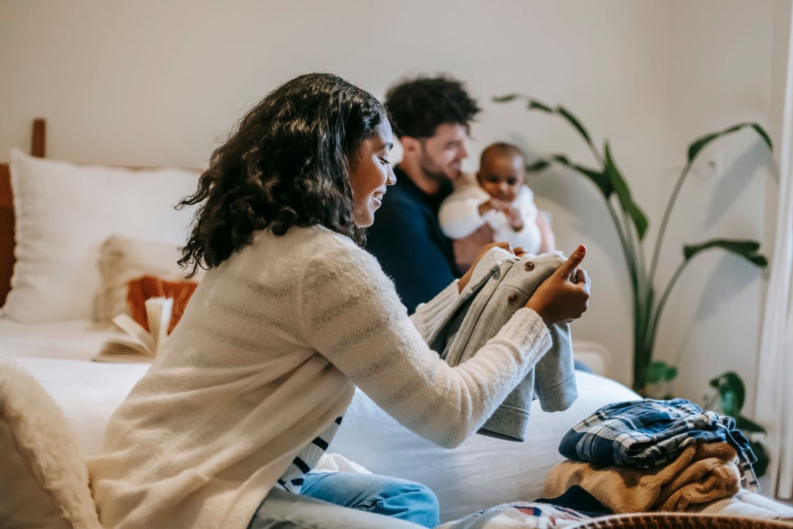 Parent sorting baby clothes on a bed