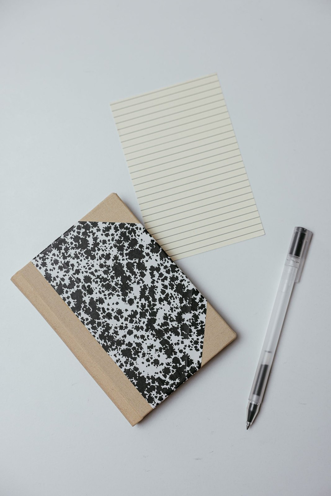 Close up shot of a notebook beside a pen on a white surface