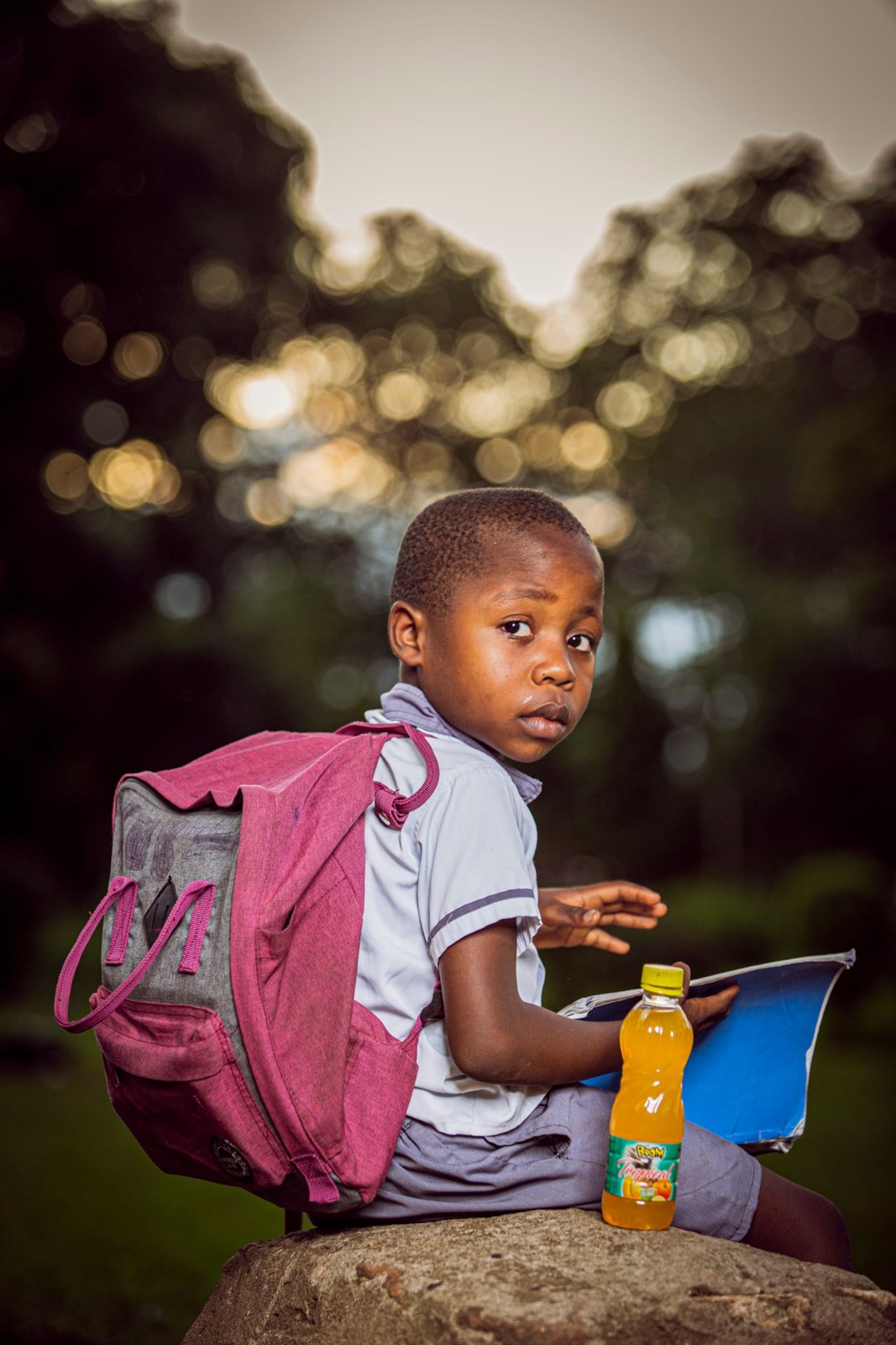 Young student outdoors with backpack and juice