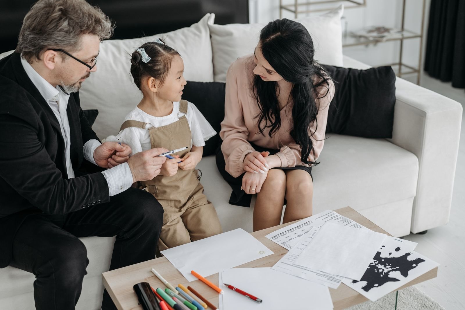 Two adults talking with a child on a sofa
