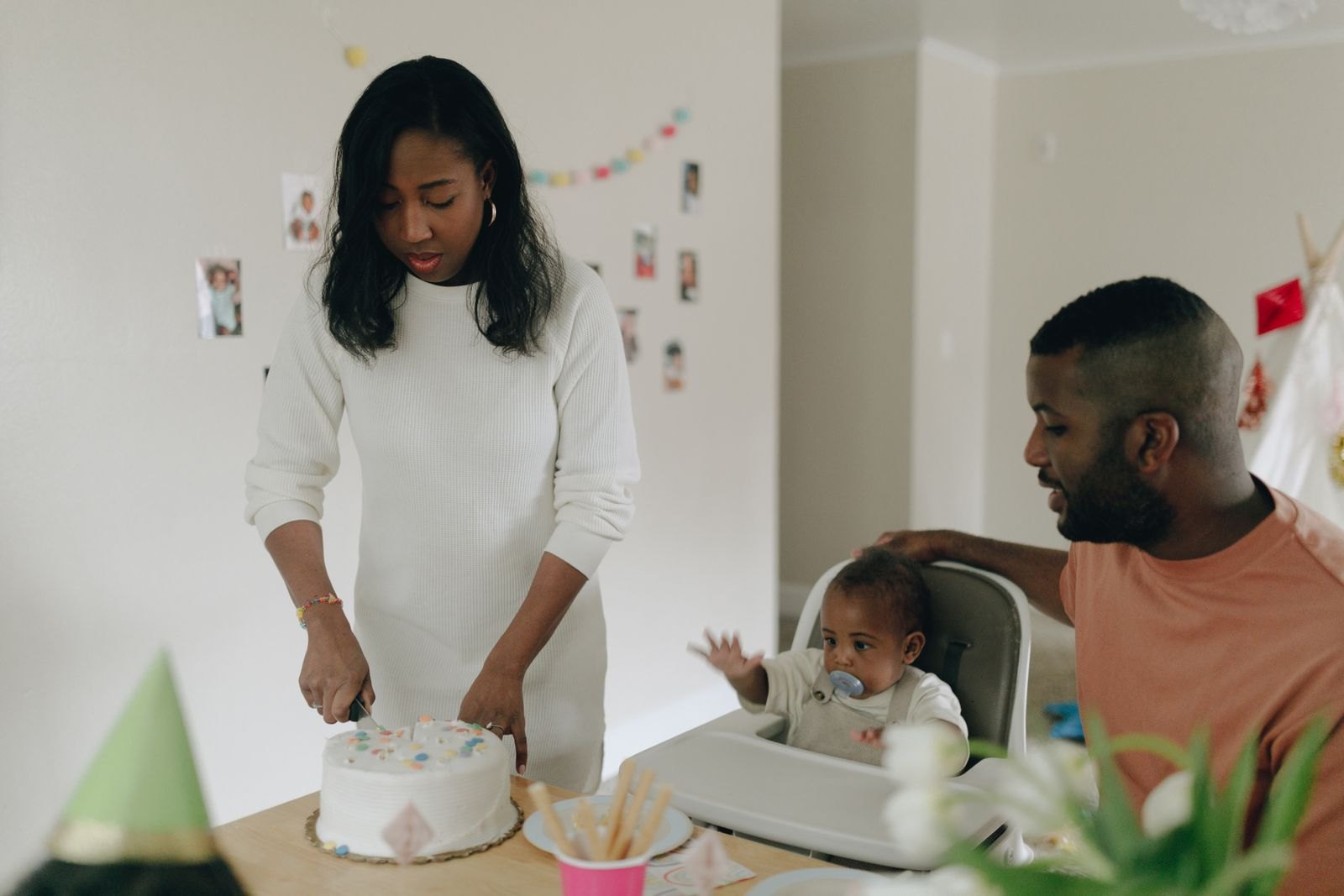 Woman slicing the cake while the man and child is looking at her