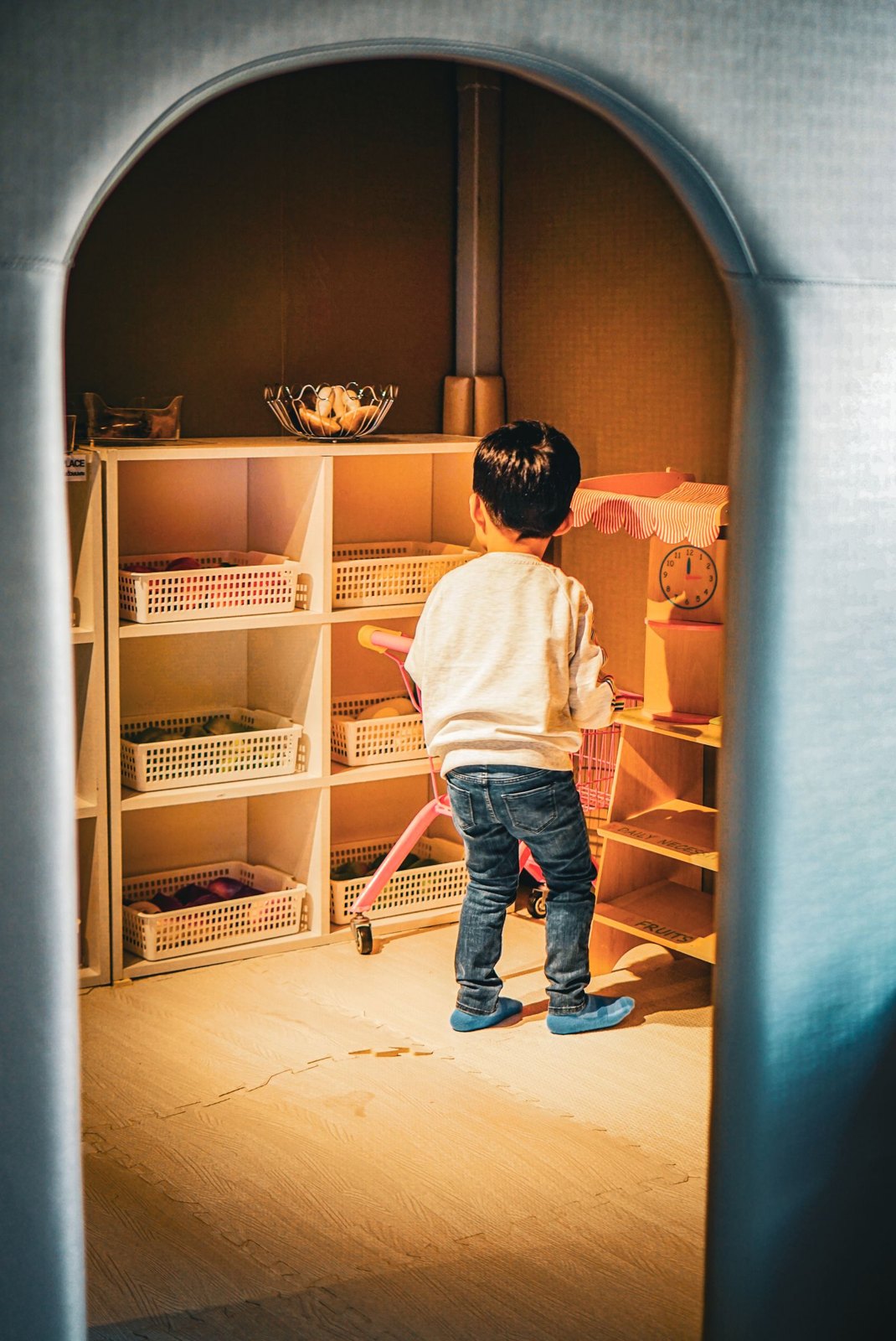 Boy standing near shelves in room