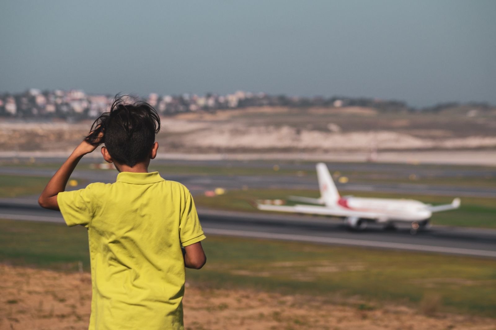 Child watching airplane takeoff at airport