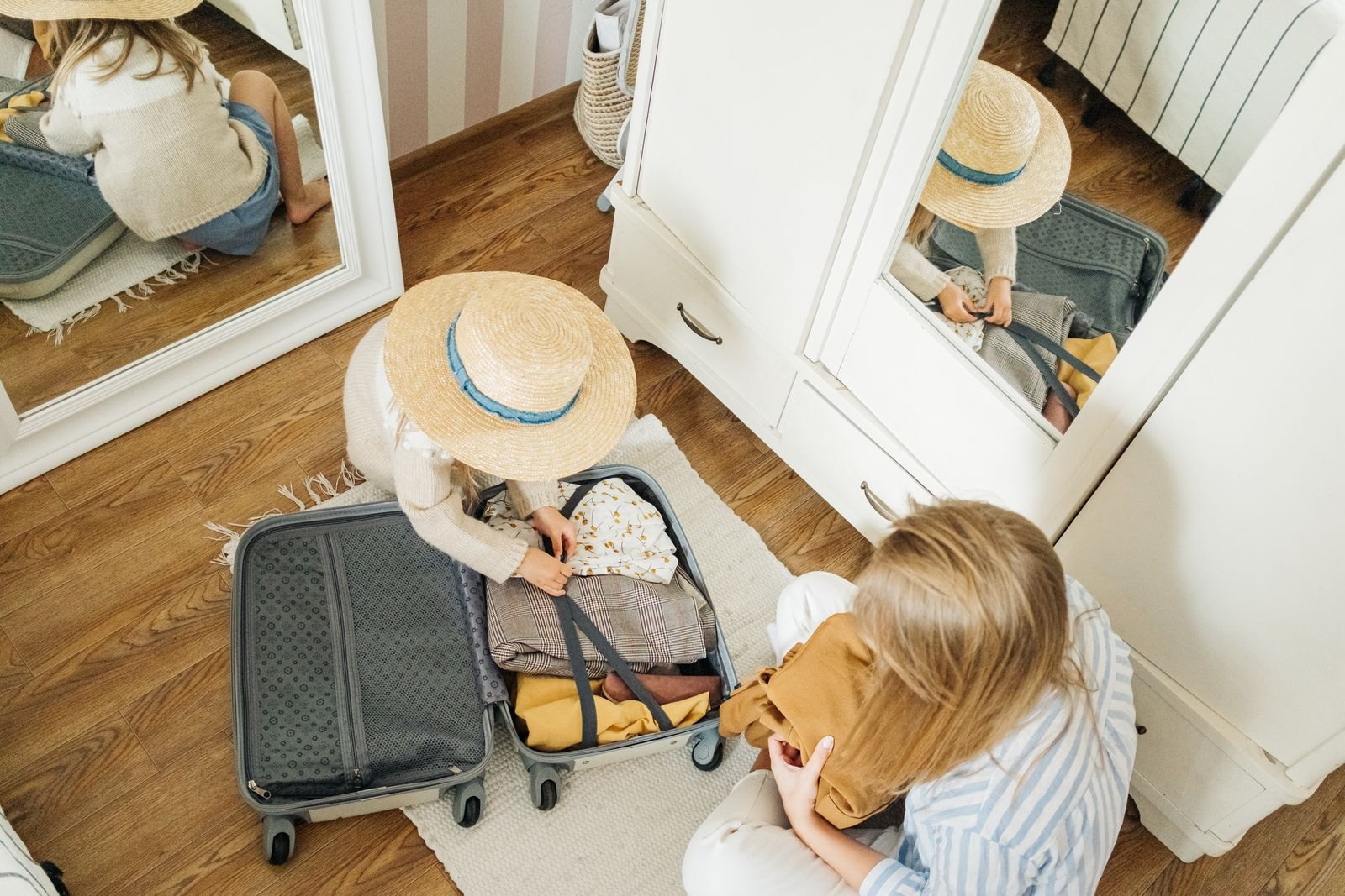 Adult and child sorting clothing beside a suitcase